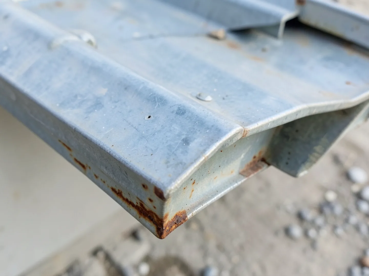 Water stains and rust streaks beneath older sectional gutter joint that has failed