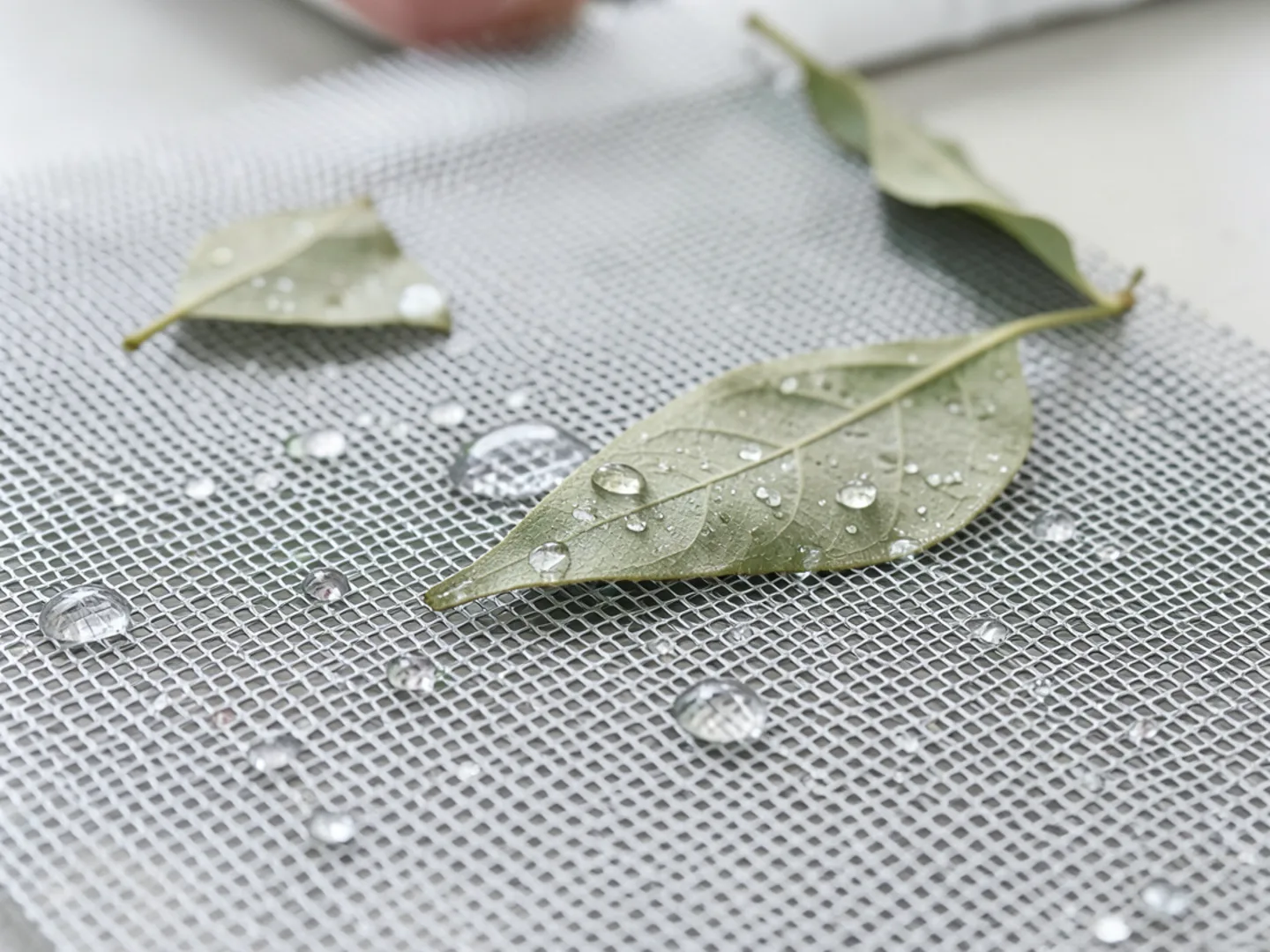 Rainwater pulling through micro-mesh openings while dry oak leaves rest on top